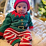 baby, child, infant, elf_costume, holiday_outfit, red_and_white_stripes, green_fleece, hat, cute, sitting, indoors, soft_blanket, festive, christmas, portrait, face, person, cozy, warm_lighting, decor