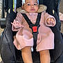 baby, infant, car_seat, seatbelt, pink_coat, white_headband, white_sandals, fur_collar, child, indoor, person, footwear, clothing, sitting, cute, young_child, baby_accessories, car_seat_strap, headwear, portrait
