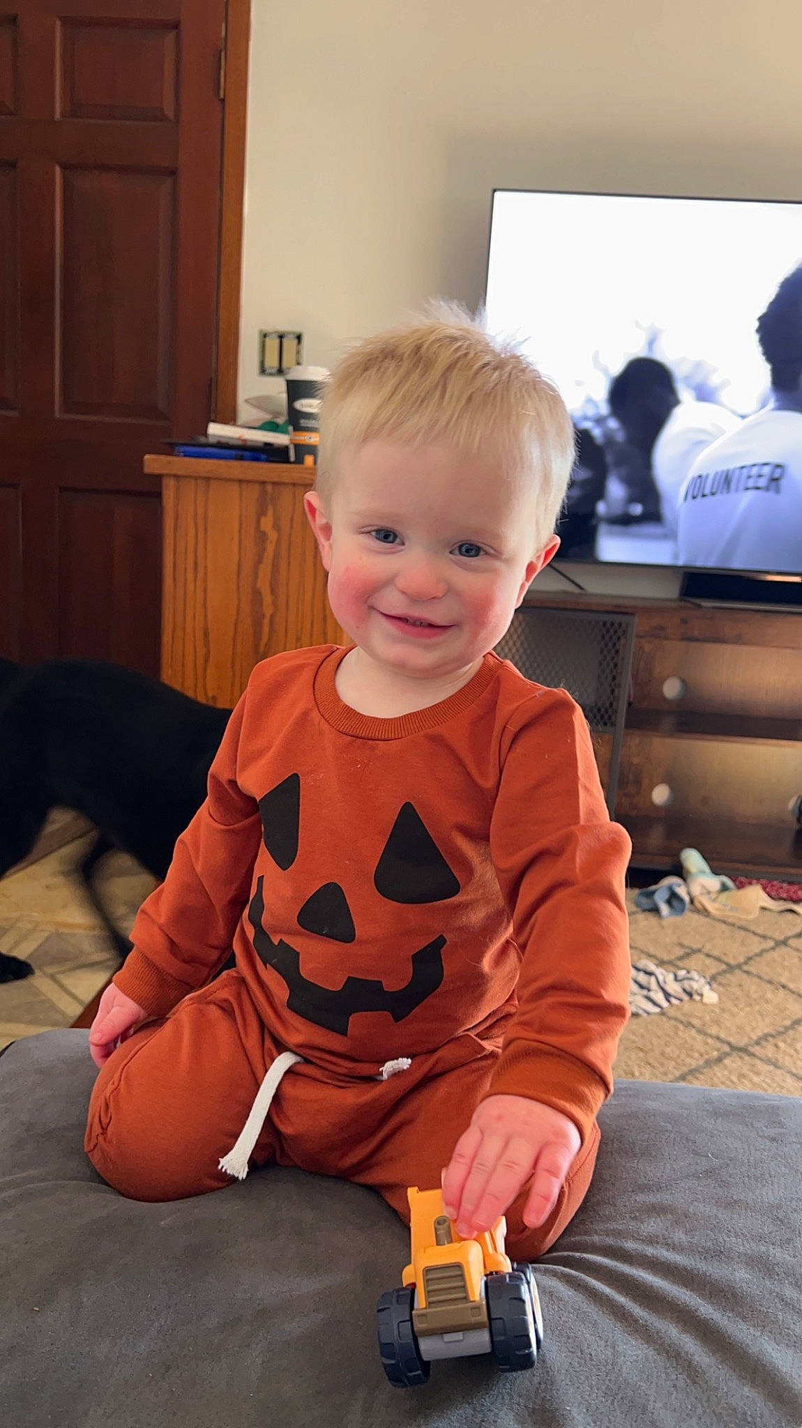 Reed is registered to the contest to win money with this photo: baby, baby_toddler_clothing, bag, cabinetry, carpet, child, event, flooring, fun, joy, lap, mammal, person, play, room, sitting, smile, standing, t_shirt, toddler