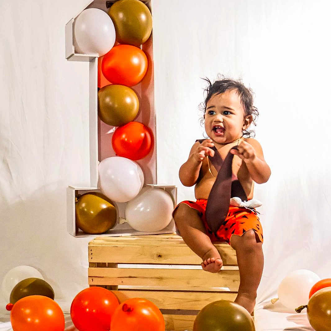 Noah is registered to the contest to win money with this photo: baby, balloon, biting, clothing, eating, face, fitness, food, happy, head, people, person, pilates, shorts, sitting, smile, sphere, sport, text, workingout
