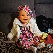 Aëlys participe au concours pour gagner de l'argent avec cette photo : baby, child, smiling, plaid_dress, white_jacket, hat, pacifier, plush_toy, leopard_print, blanket, sitting, indoors, cute, person, face, headwear, cozy, comfort, home, young_child