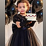 balloons, birthday_cake, black_dress, black_gloves, candle, celebration, child, curly_hair, cute, earrings, festive, girl, holding, indoor, party, portrait, smile, tiara, tulle_skirt, young