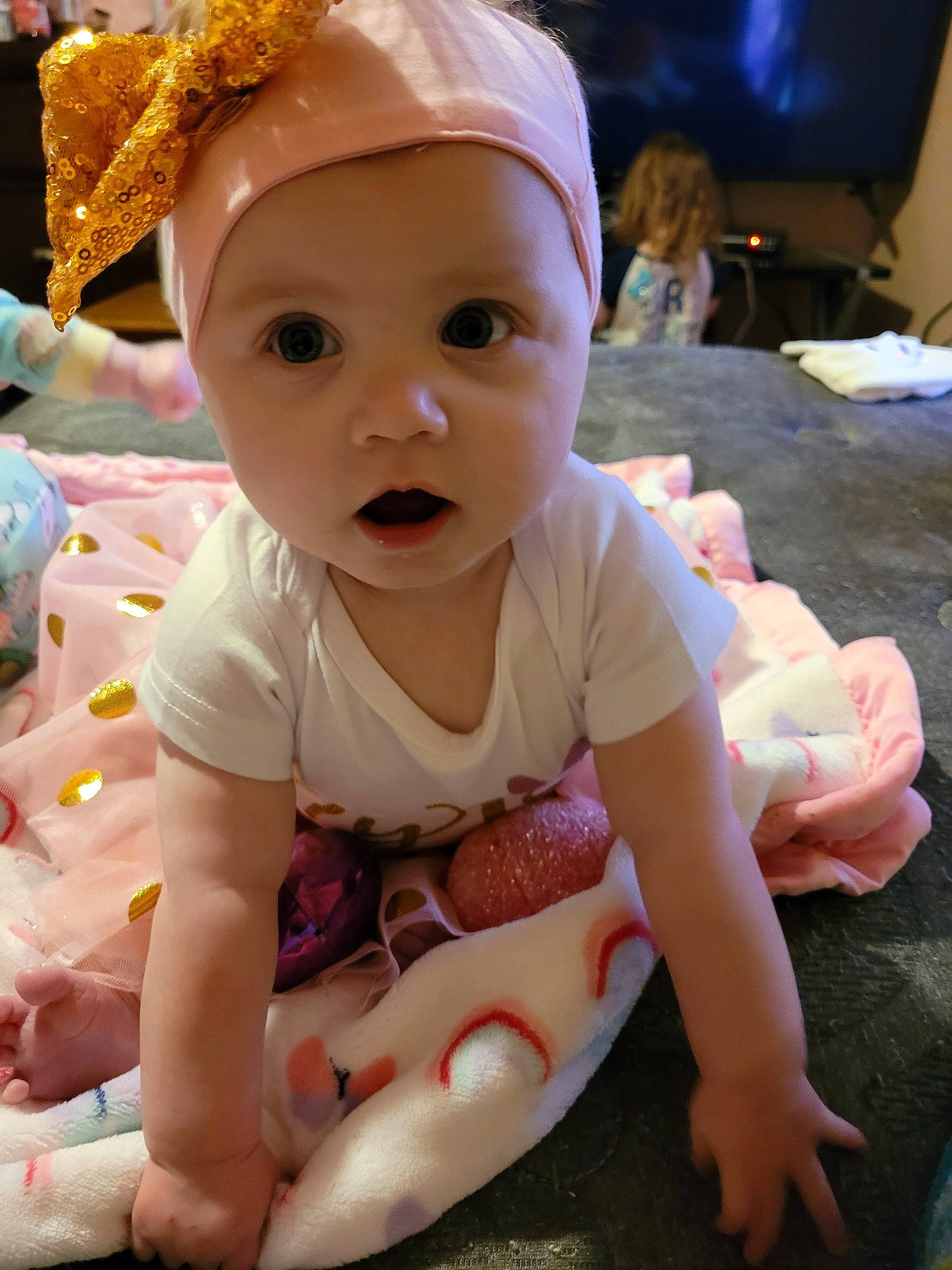 Maci is registered to the contest to win money with this photo: baby, baby_toddler_clothing, cable_television, cap, cheek, child, event, foot, fun, happy, headwear, led_backlit_lcd_display, pattern, person, pink, room, sitting, skin, television, toddler