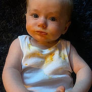 Rosie-May is registered to the contest to win money with this photo: baby, child, infant, face, eyes, white_tank_top, food_stains, hands, feet, floral_pants, sitting, curious, indoors, portrait, cute, expression, skin, person, young, exploration