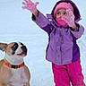 child, dog, snow, winter, gloves, jacket, hat, scarf, playful, outdoor, cold, pet, animal, fun, young, cute, expression, colorful_clothing, snowy_background, winter_activity