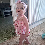 Judith participe au concours pour gagner de l'argent avec cette photo : toddler, child, barefoot, indoor, headband, pink_clothing, romper, floor, radiator, doorway, smile, happy, baby, person, home, curly_hair, standing, cheerful, cute, exploring