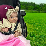 Maddison is registered to the contest to win money with this photo: baby, child, stroller, headband, bow, blanket, outdoor, greenery, grass, smile, cute, infant, clothing, seatbelt, park, nature, portrait, happy, person, babyclothes