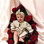 baby, infant, roses, red_roses, flowers, headband, cream_outfit, smiling, happy, cute, soft_fabric, portrait, child, one_child, sitting, indoors, flower_bed, closeup, skin, celebration