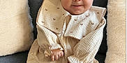 Maddison is registered to the contest to win money with this photo: baby, child, couch, cozy, cute, dress, face, hands, happy, headband, home_interior, indoors, infant, legs, neutral_colors, pillow, portrait, seated, smiling, soft_texture