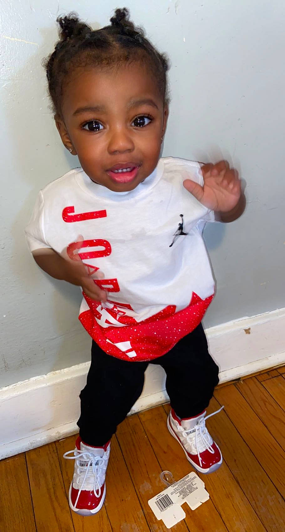 Jakobe is registered to the contest to win money with this photo: active_pants, baby_toddler_clothing, cheek, eye, face, flooring, gesture, hair, happy, human_leg, joint, knee, person, shoe, sleeve, sportswear, t_shirt, thigh, toddler, white