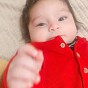 Dariel Guancela joined the competition — help win amazing prizes! baby, blanket, button, cheeks, child, closeup, cozy, cute, eyes, face, hair, hand, indoors, infant, lying_down, portrait, reach, red_sweater, skin, smile