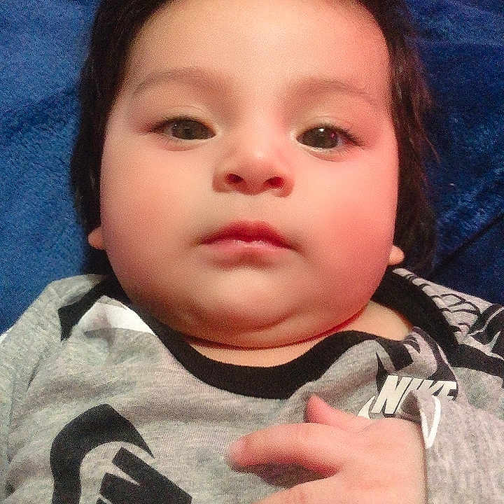 Dariel Cruz joined the competition — help win amazing prizes! baby, blanket, blue_blanket, cheeks, child, chubby_cheeks, close_up, clothing, eyes, face, gaze, hair, hand, indoors, infant, laying_down, lips, nike_logo, onesie, portrait