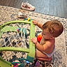 baby, baby_playing, blocks, brown_hair, carpet, child, diaper, floor, furniture, home, indoor, orange_ball, playing, profile, rug, shoes, sitting, toddler, toy, toy_frame