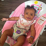 Maya joined the competition — help win amazing prizes! baby, smiling, curly_hair, baby_seat, pink, cute, infant, happy, child, indoor, clothing, bracelet, wooden_floor, footwear, bib, animal_print, rainbow, monkey, sun, toddler