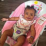 baby, smiling, curly_hair, baby_seat, pink, cute, infant, happy, child, indoor, clothing, bracelet, wooden_floor, footwear, bib, animal_print, rainbow, monkey, sun, toddler