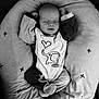 baby, sleeping, onesie, elephant, heart, pillow, cushion, pattern, star, black_and_white, infant, child, clothing, soft, peaceful, resting, cute, portrait, babywear, cozy