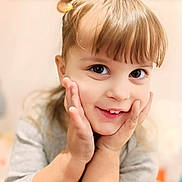 Louna a rejoint le concours — aidez-le/la à gagner de superbes lots ! blonde_hair, casual_clothing, child, closeup, cute, expression, eyes, face, hair, hands, happy, indoors, innocence, light_skin, person, playful, portrait, smiling, soft_background, young