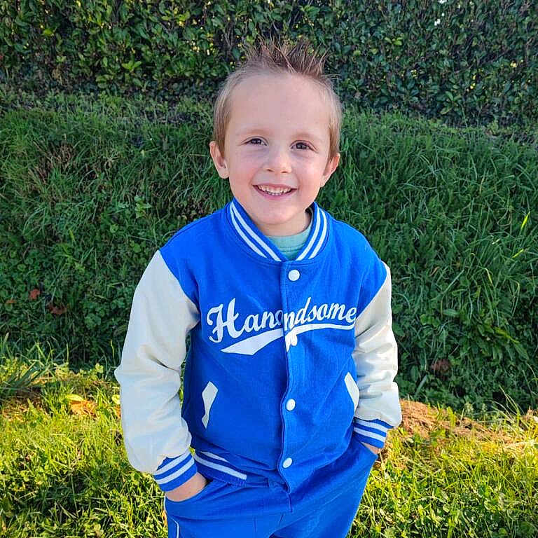 Léo participe au concours pour gagner de l'argent avec cette photo : blue_jacket, boy, casual_clothing, child, confident, cute, daylight, fashion, grass, greenery, hands_in_pockets, happy, hedge, outdoor, portrait, smiling, spiked_hair, standing, sunlight, young