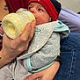 baby, infant, bottle, feeding, hat, red_hat, clothing, hand, tattoo, person, jeans, blanket, indoor, face, feeding_bottle, holding, closeup, cute, newborn, warm