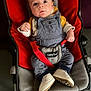baby, child, infant, overalls, white_shoes, baby_seat, red, gray, yellow, curious_expression, indoor, clothing, seatbelt, cute, person, young_child, car_seat, straps, casual, portrait