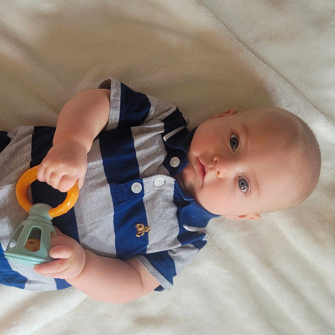 Elijah is registered to the contest to win money with this photo: baby, bed, blanket, bodypart, clothing, couch, crib, cutlery, face, finger, furniture, hand, head, infantbed, person, photography, portrait, spoon, t_shirt, toy
