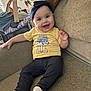 baby, blanket, child, couch, cozy, cute, furniture, happy, headband, home, indoor, infant, living_room, pants, person, portrait, smiling, socks, toy, yellow_shirt