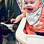 animal, baby, bib, blanket, chair, child, cute, dog, face, floor, hand, happy, high_chair, indoor, looking, orange_clothing, person, pet, playful, smiling