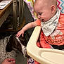 animal, baby, bib, blanket, chair, child, coral_shirt, curious, dog, floor, hand, happy, high_chair, indoor, interaction, patterned_bib, person, petting, smile, table