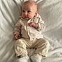 baby, infant, clothing, shirt, pants, shoes, blanket, lying_down, face, expression, cute, small_hands, footwear, soft_texture, indoors, child, portrait, comfortable, curious, casual