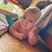 Victoria a rejoint le concours — aidez-le/la à gagner de superbes lots ! baby, infant, floor, blanket, hand, face, eyes, curious, indoors, wooden_floor, soft_texture, clothing, child, portrait, resting, cushion, home, natural_light, young, cute