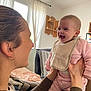 Louise participe au concours pour gagner de l'argent avec cette photo : baby, infant, smile, laugh, person, adult, holding, indoor, living_room, curtains, window, furniture, bib, clothing, pink_outfit, happy, face, head, hands, home