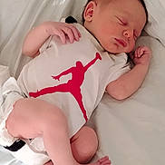 Kash is registered to the contest to win money with this photo: newborn, baby, sleeping, infant, onesie, white_bed, blanket, soft_lighting, peaceful, curled_up, skin, hand, foot, bedroom, indoors, clothing, portrait, relaxation, cute, rest