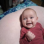 Piper is registered to the contest to win money with this photo: baby, infant, child, smiling, happy, portrait, face, blue_eyes, lying_down, blanket, pink_blanket, red_clothing, long_sleeves, hand, indoor, home, bed, bedding, close_up, candid