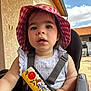 Zoé a rejoint le concours — aidez-le/la à gagner de superbes lots ! building, child, clothing, clouds, curious, daylight, expression, hat, high_chair, outdoor, person, playful, ruler, seat, sky, straps, summer, sun_hat, table, toddler