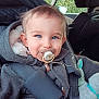 Timaël participe au concours pour gagner de l'argent avec cette photo : child, toddler, pacifier, car_seat, car_interior, blue_eyes, coat, hood, plush_toy, safety_belt, buckle, smiling, portrait, close_up, baby, infant, chubby_cheeks, ear, clothing, seatbelt_strap
