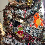 Gravy is registered to the contest to win money with this photo: cat, christmas_tree, ornaments, grinch_doll, charmander_plush, holiday, decorations, tinsel, ribbon, candy_cane, lights, indoor, festive, greenery, snow_flocked, red_bauble, gold_baubles, plush_toy, pet, curious