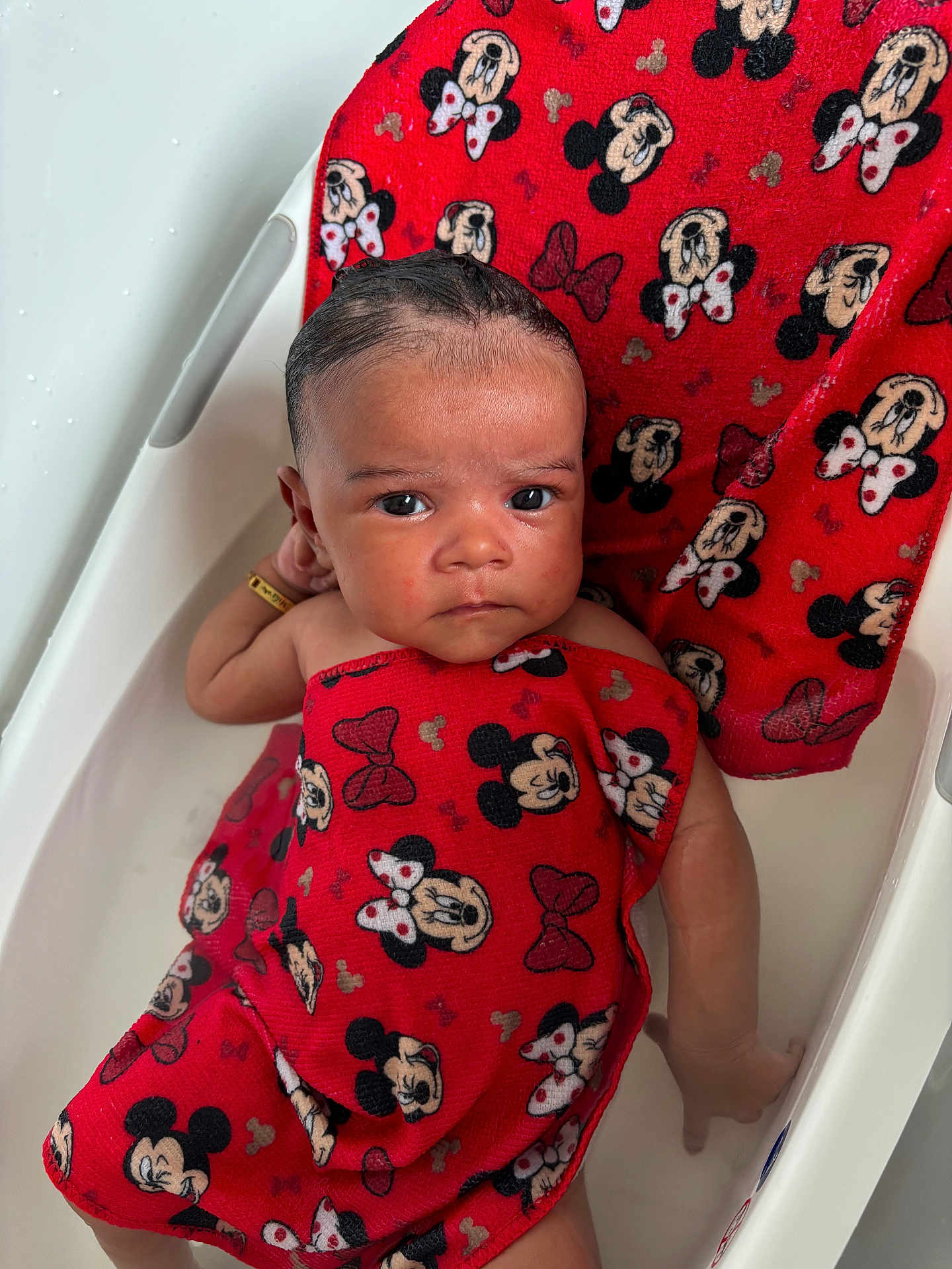 Mila is registered to the contest to win money with this photo: baby, bathtub, towel, red, mickey_mouse, minnie_mouse, water, child, bath, skin, face, expression, hand, relaxing, cute, infant, indoors, person, small, cute_expression