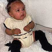 Mila Abbott joined the competition — help win amazing prizes! baby, child, infant, knitwear, black_socks, white_blanket, cozy, cute, portrait, indoors, curly_hair, bracelet, bow, sitting, soft_texture, expression, furniture, candid, adorable, warm_clothing