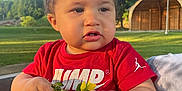 Amir is registered to the contest to win money with this photo: child, toddler, baby, red_shirt, flowers, outdoor, daylight, greenery, bench, park, person, curly_hair, holding, nature, sunlight, casual_clothing, cute, skin, portrait, summer