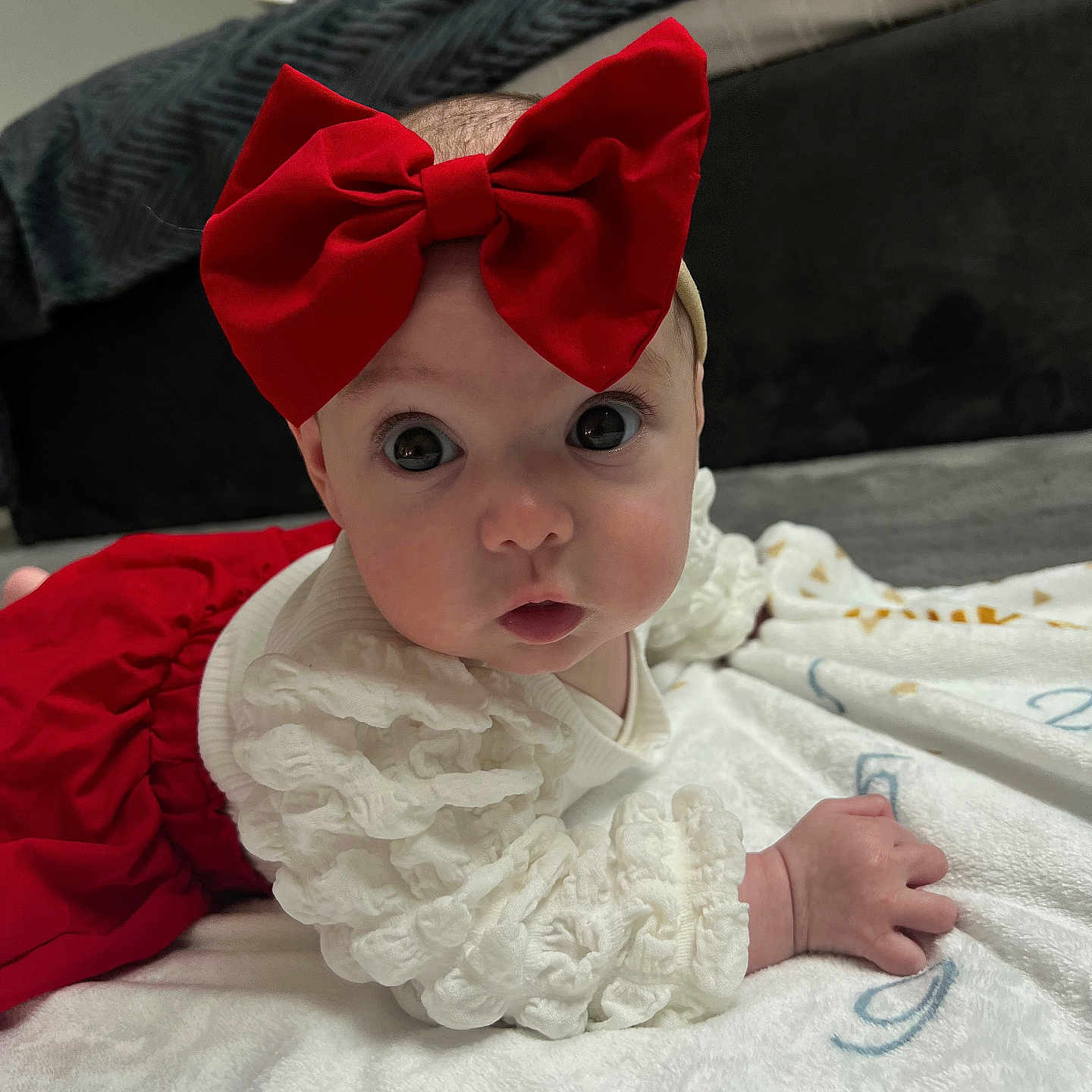 Lana a rejoint le concours — aidez-le/la à gagner de superbes lots ! adorable, baby, big_eyes, blanket, child, clothing, curious, cute, face, hand, headband, indoor, infant, lying_down, portrait, red_bow, red_skirt, skin, soft_texture, white_top
