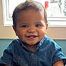 Kennedy is registered to the contest to win money with this photo: baby, child, smiling, happy, portrait, indoors, window, denim, shirt, bee, embroidered, seated, face, eyes, hair, infant, daylight, photography, close_up, person