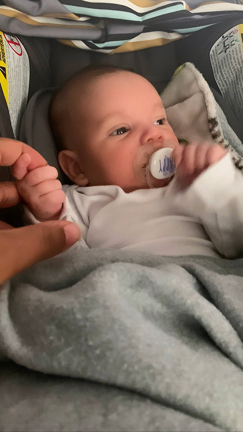 Orion is registered to the contest to win money with this photo: baby, baby_products, baby_toddler_clothing, car_seat, cheek, child, comfort, ear, finger, gesture, hand, linens, mouth, nail, person, product, sitting, skin, sleeve, thumb