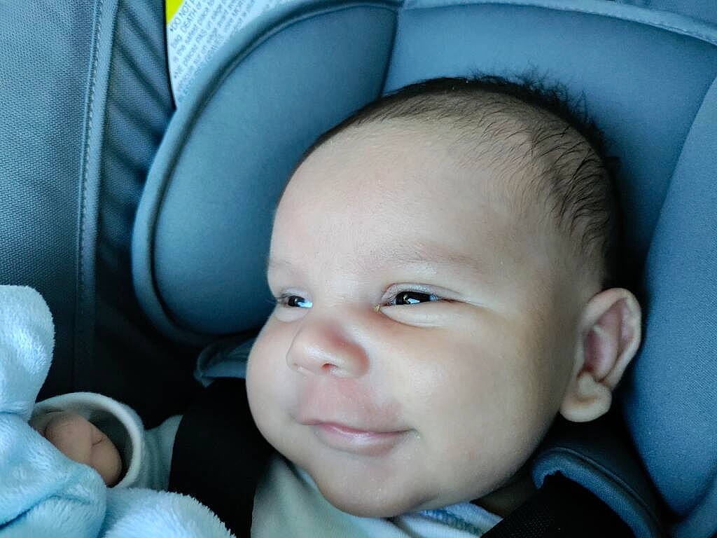 Orion is registered to the contest to win money with this photo: auto_part, baby, baby_carriage, baby_in_car_seat, baby_products, blue, car_seat, cheek, child, comfort, electric_blue, face, happy, head_restraint, nose, person, seat_belt, skin, smile, toddler