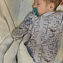 baby, sleeping, pacifier, onesie, dinosaur_pattern, blanket, bed, infant, cozy, child, cute, resting, soft, clothing, newborn, peaceful, indoors, portrait, comfort, toddler