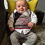 Nolan participe au concours pour gagner de l'argent avec cette photo : baby, child, sitting, couch, pillow, smile, white_shirt, sweater_vest, gray_pants, socks, indoor, face, portrait, cute, infant, happy, furniture, cozy, home, relaxed