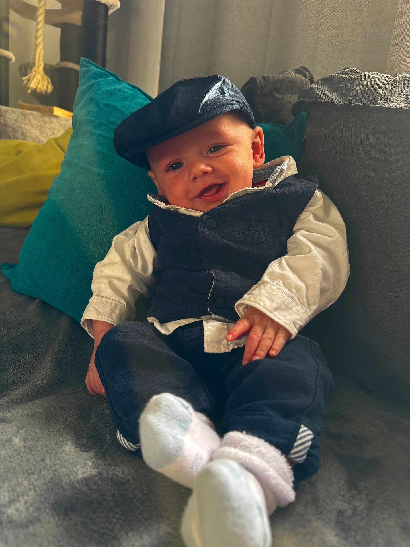 Nolan participe au concours pour gagner de l'argent avec cette photo : baby, child, smiling, couch, pillows, hat, vest, white_shirt, socks, indoor, cozy, happy, portrait, seated, furniture, cute, infant, clothing, relaxed, home