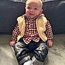 Nolan a rejoint le concours — aidez-le/la à gagner de superbes lots ! baby, smiling, indoor, couch, clothing, vest, checkered_shirt, jeans, socks, happy, child, person, portrait, casual, seated, window, soft_lighting, cozy, cute, infant