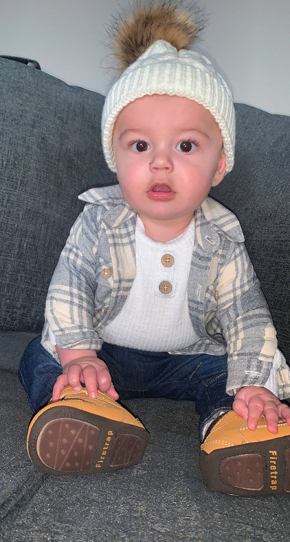 Cole is registered to the contest to win money with this photo: baby, baby_toddler_clothing, cap, cheek, comfort, dress, headwear, iris, lip, nose, pattern, person, plaid, sitting, skin, sleeve, surprise, tartan, textile, toddler