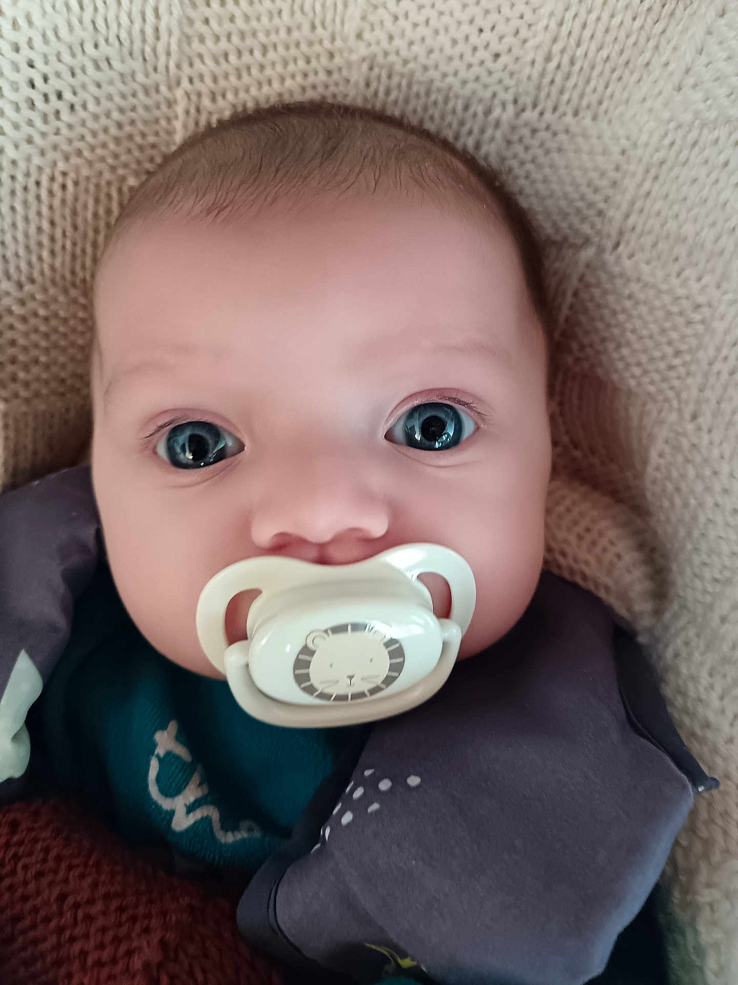 Andréa participe au concours pour gagner de l'argent avec cette photo : baby, infant, pacifier, blue_eyes, close_up, portrait, knit_blanket, newborn, face, cute, cheeks, staring, indoors, fabric, clothing, sleeve, head, mouth, eyelashes, portraitphotography