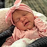 baby, sleeping, pink_headband, pink_clothing, blanket, cozy, infant, cute, portrait, face, child, soft_texture, indoor, resting, newborn, hand, peaceful, closeup, adorable, toddler